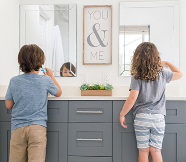 Twee kinderen poetsen hun tanden voor de spiegel en gebruiken daarna de rich smile UV-beschermhoes